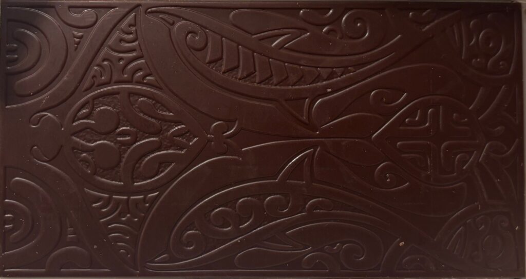 Unwrapped Tahiti dark chocolate bar with intricate floral patterns carved into bar